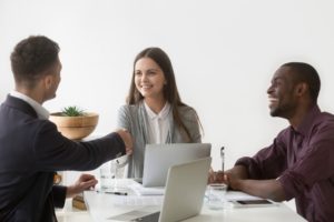 smiling businesswoman shaking hand male partner group meeting group