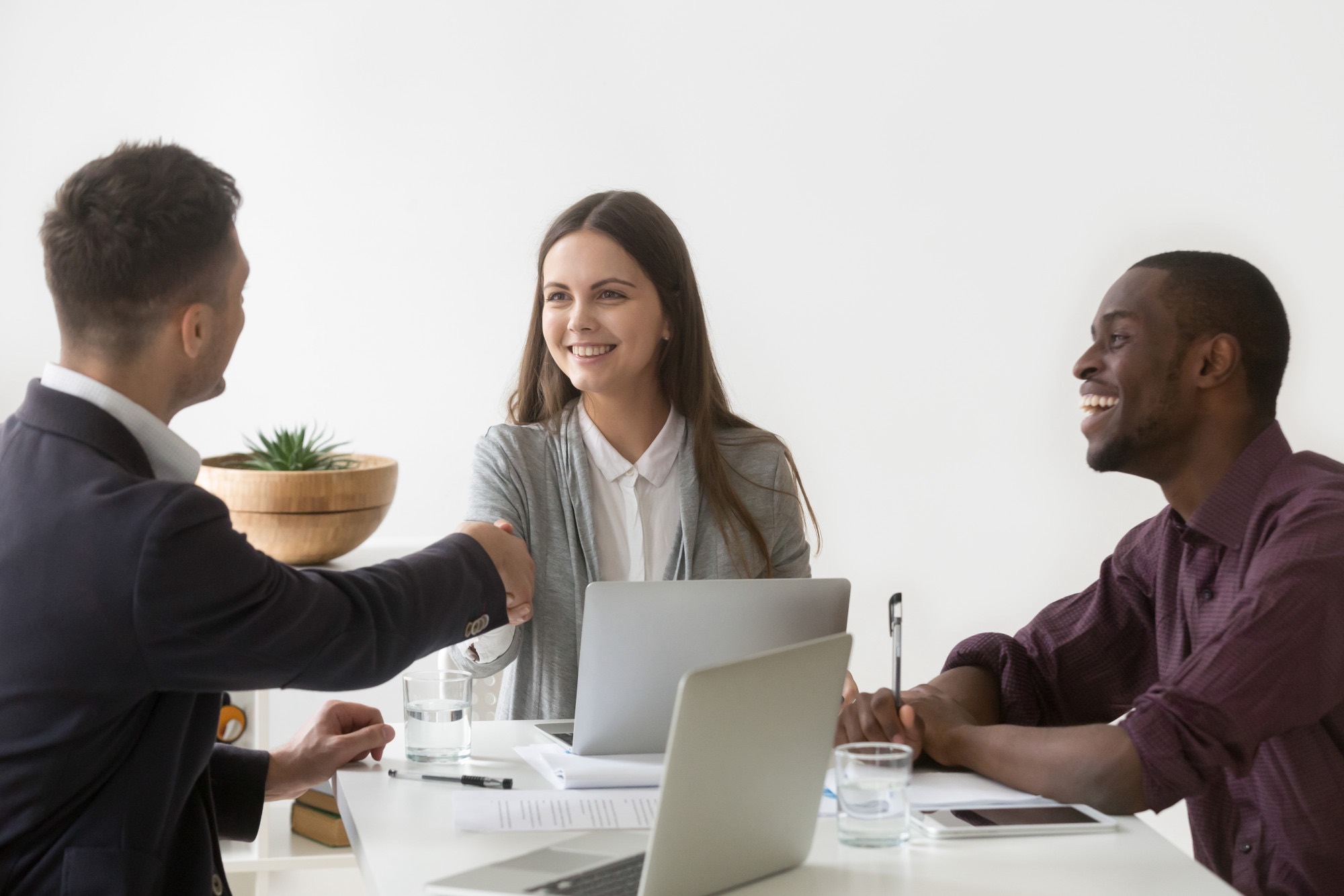 smiling businesswoman shaking hand male partner group meeting group